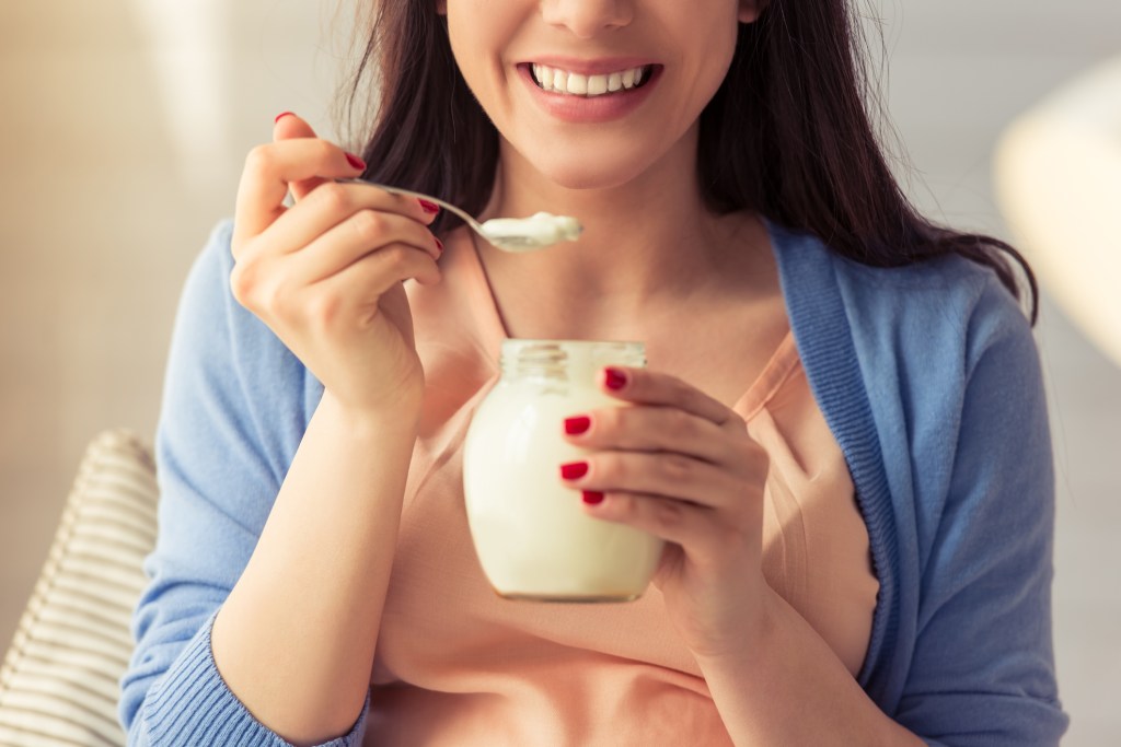 Mulher comendo iogurte Confira 6 alimentos “saudáveis” que podem conter açúcar