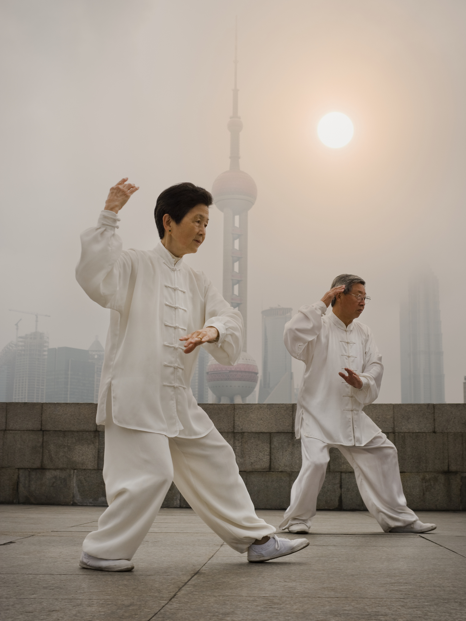 Couple doing tai chi outdoors with city skyline in background -