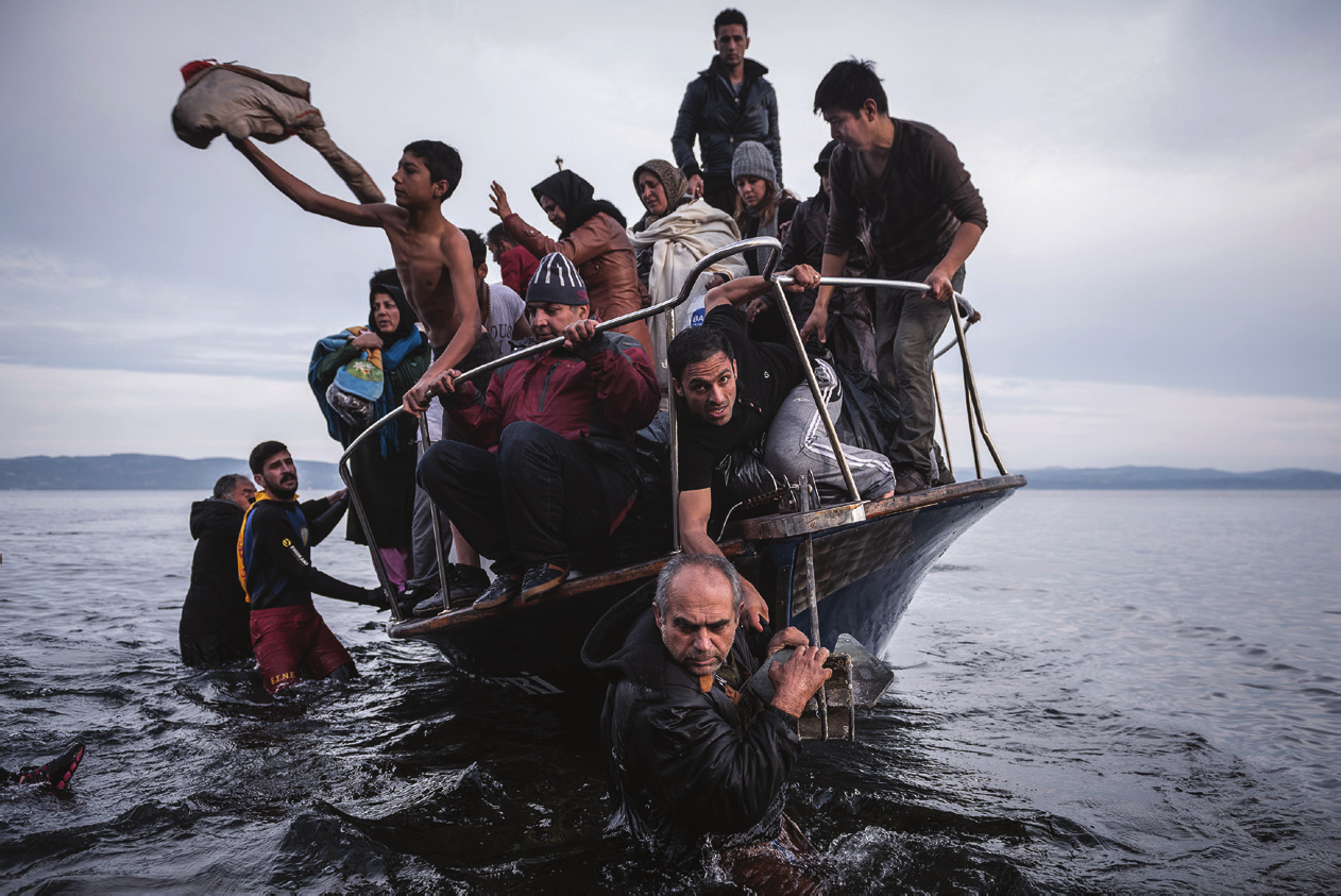 A ROTA ATÉ A EUROPA: Na guerra entre o regime sírio, rebeldes e extremistas, a população fica no meio de um violento fogo cruzado. Acima, a imagem mostra uma garota síria ferida em bombardeio das forças do governo, em tratamento em um hospital improvisado na cidade de Douma. Muitas pessoas não suportam a situação e decidem abandonar o país, como mostra a imagem abaixo de uma pequena embarcação chegando à vila de Skala, na Ilha de Lesbos, na Grécia. Já a foto premiada, na página ao lado, revela os obstáculos que os refugiados recém-chegados à Europa são submetidos para conseguir recomeçar suas vidas.