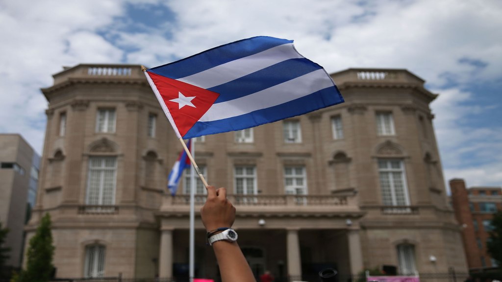 Homem balança bandeira de Cuba em frente a embaixada do país em Washington, capital dos Estados Unidos 