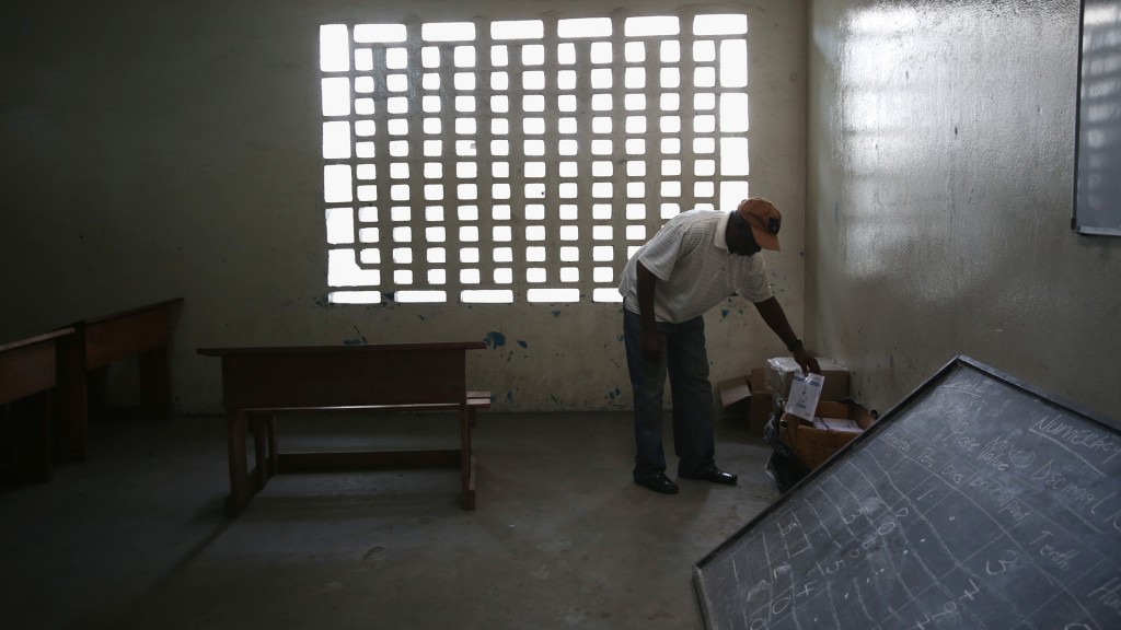 Um funcionário do serviço de saúde na Libéria pega um livro em uma sala de aula anteriormente usada como centro de atendimento para pacientes com ebola. Foto: Getty Images.