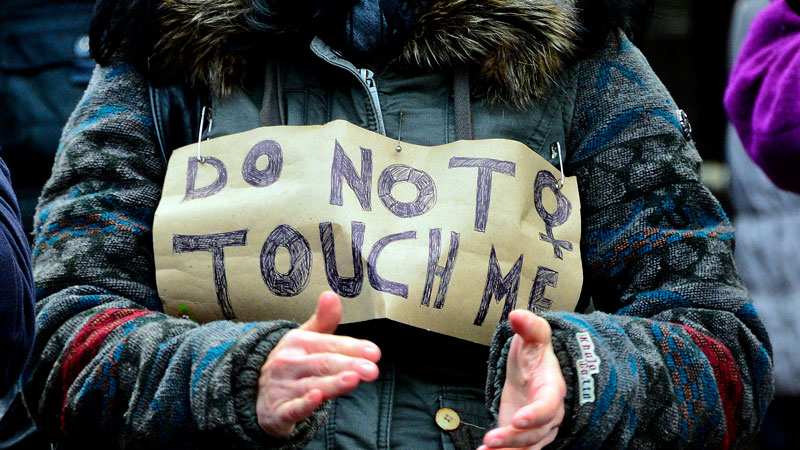 Mulher carrega placa com os dizeres "Não toque em mim" em protesto contra ataques no Ano-Novo (Getty Images)