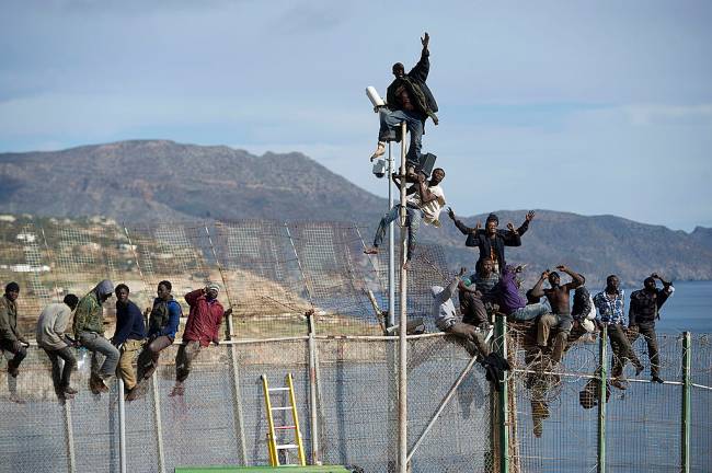 Imigrantes africanos escalam a cerca que separa Marrocos do enclave espanhol de Melilla, em 2014 (foto: Alexander Koerner/Getty Images)